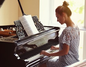 Lady playing piano with sheet of music